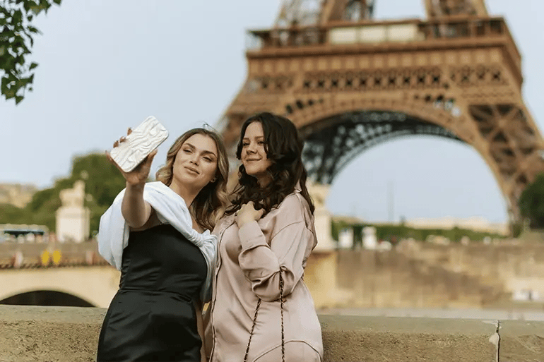 two friends taking a photo in front of the Eiffel Tower