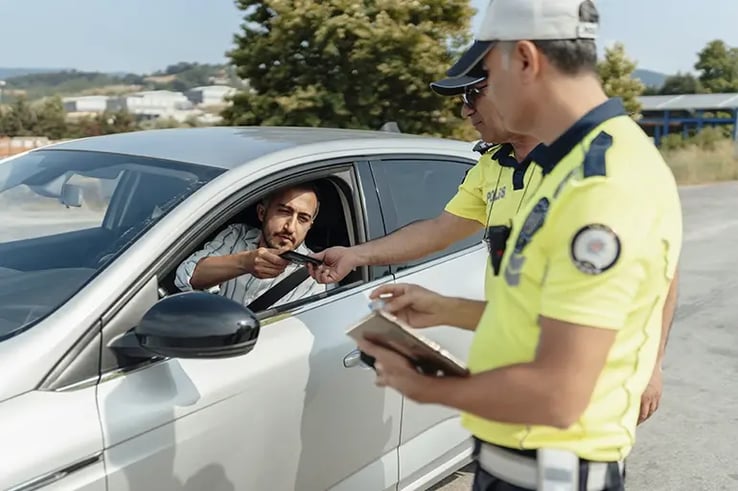 police handing some papers to a man in his car