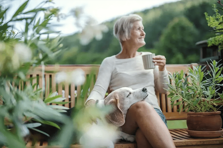 a lady having a coffee in her garden with her dog