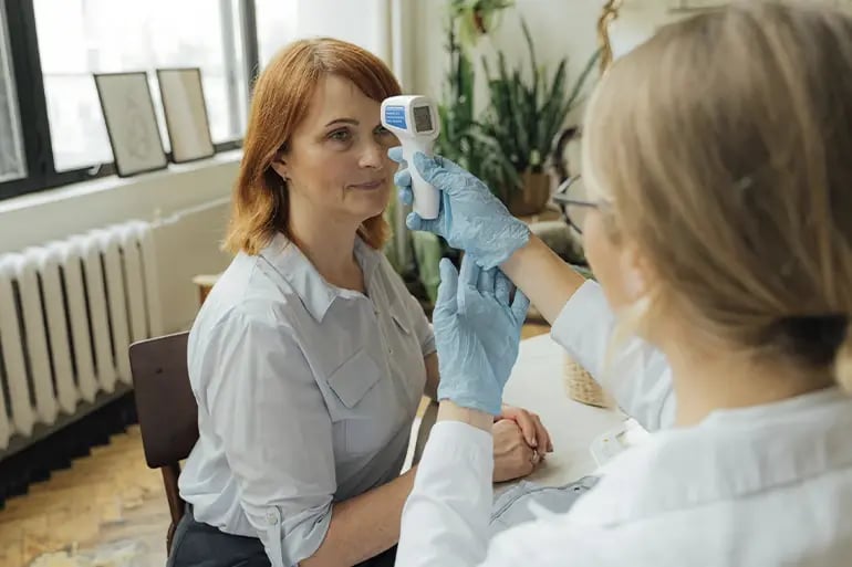 a doctor taking a woman's temperature with a thermometer