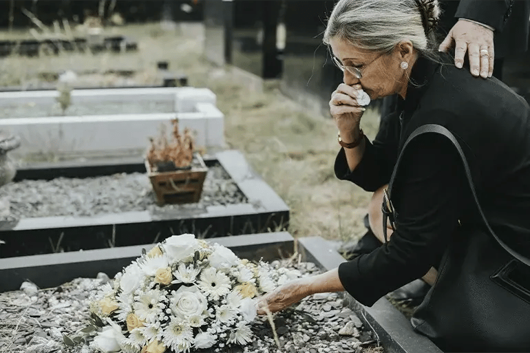 a lady leaving a bouquet of flowers for a deceased person