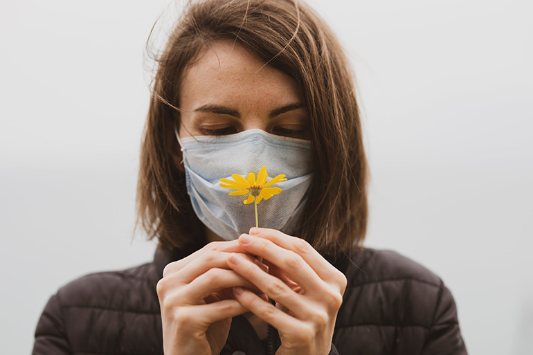 Woman looking at a flower thinking of allergy testing in Spain