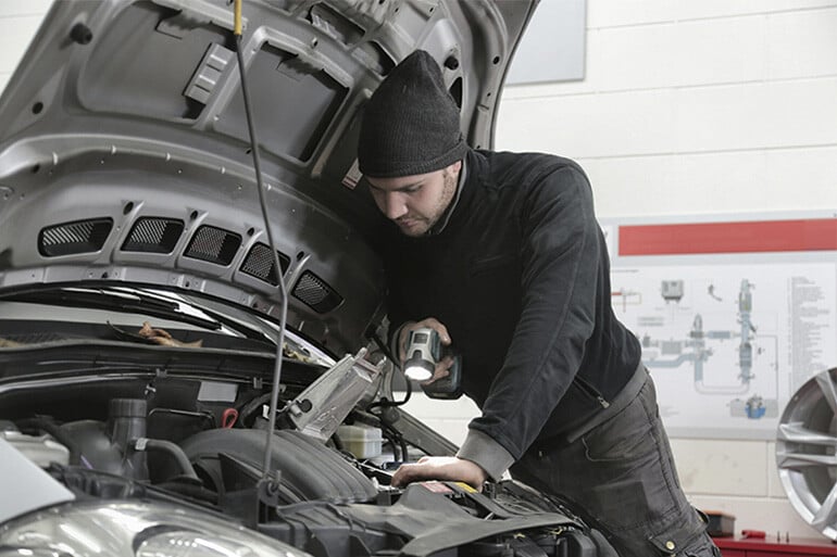 A mechanic repairing the car after the girl knew what to do when her car broke down in Spain.