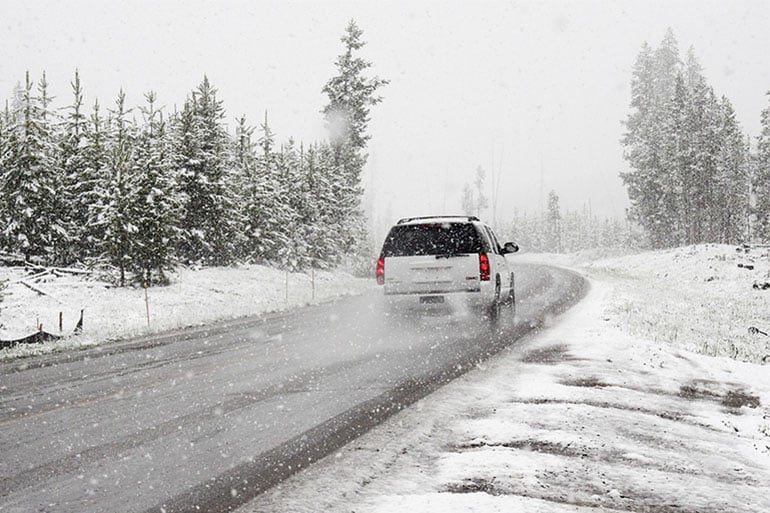 A car starting its journey after making sure to follow road safety tips for snow and winter.
