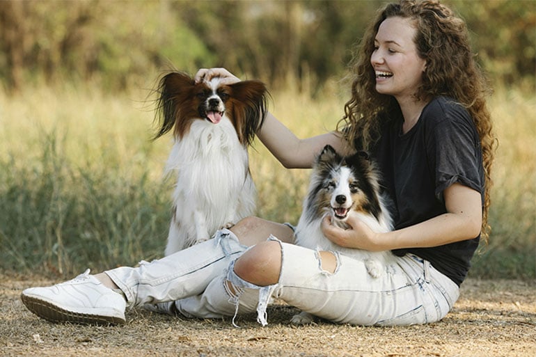  A woman with her dogs after learning the importance of pet insurance for vaccinations.