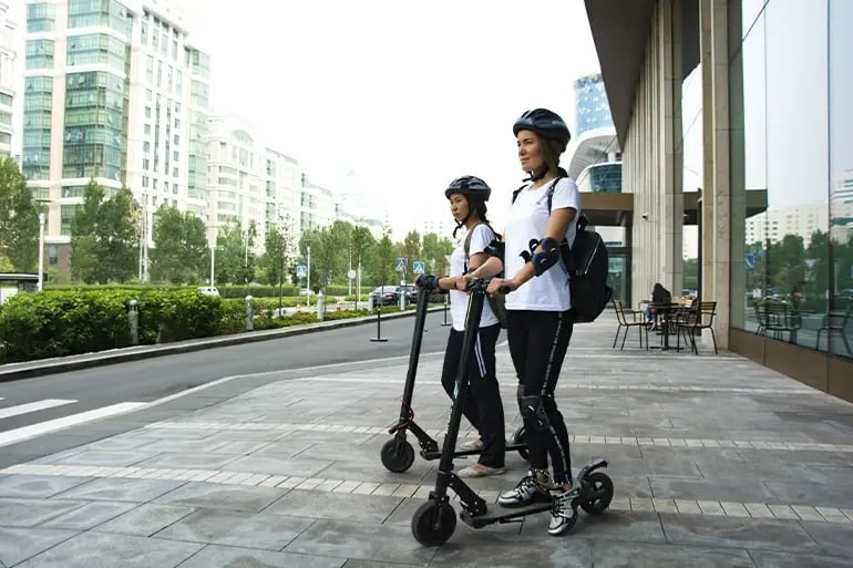 Two friends enjoying their ride after purchasing their electric scooter insurance.
