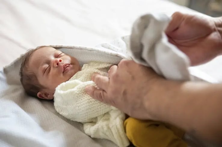 A sleeping baby with all the essentials for a newborn