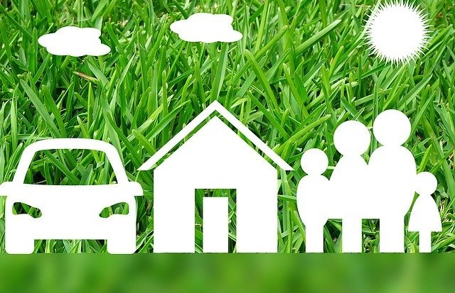 image of green grass with white images of clouds, sun, a car, a house and a family