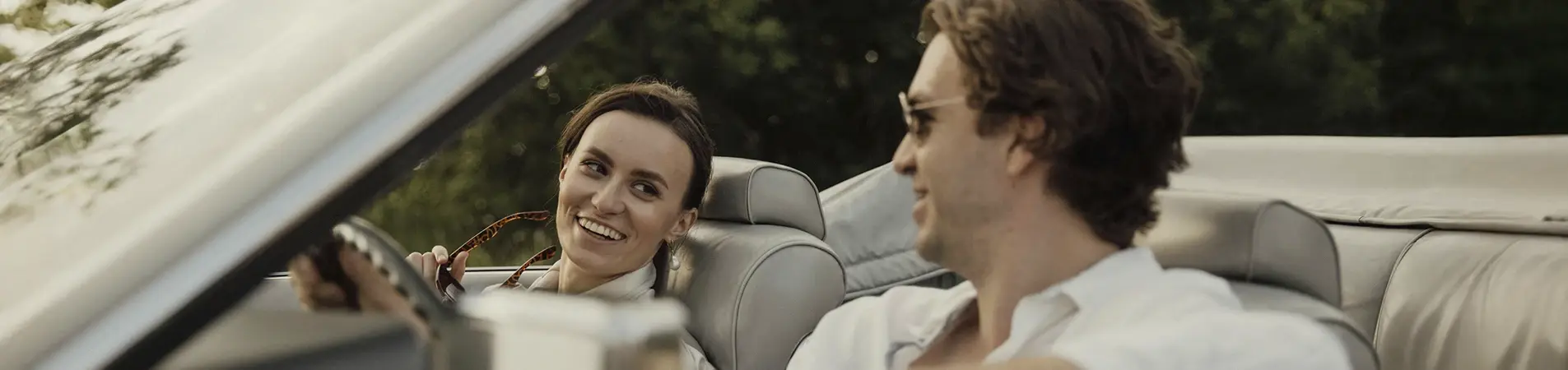 a man and a woman riding in a convertible vehicle
