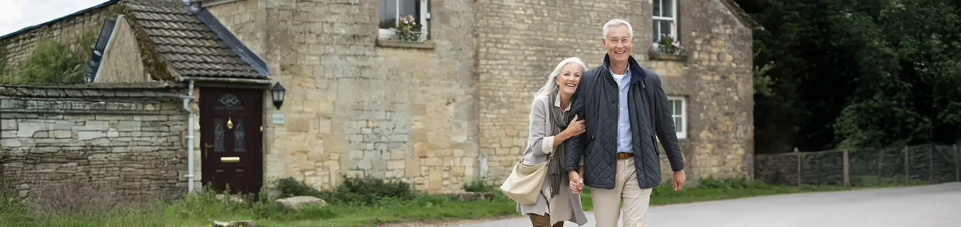 an elderly couple posing in front of their house