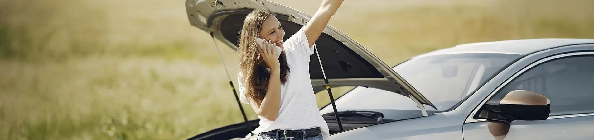 woman talking on the phone due to a breakdown in her vehicle