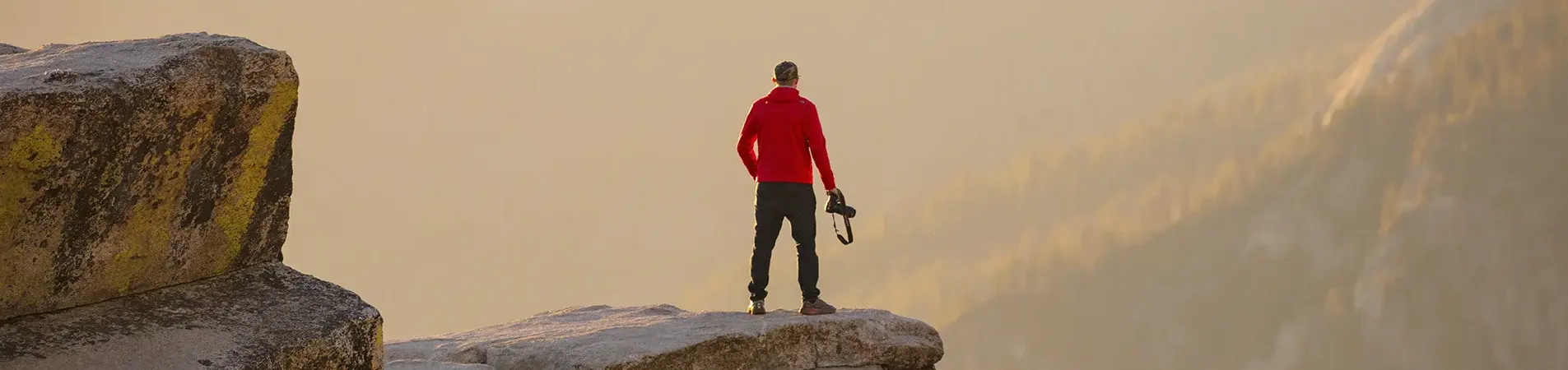 a man on the edge of a cliff at sunset