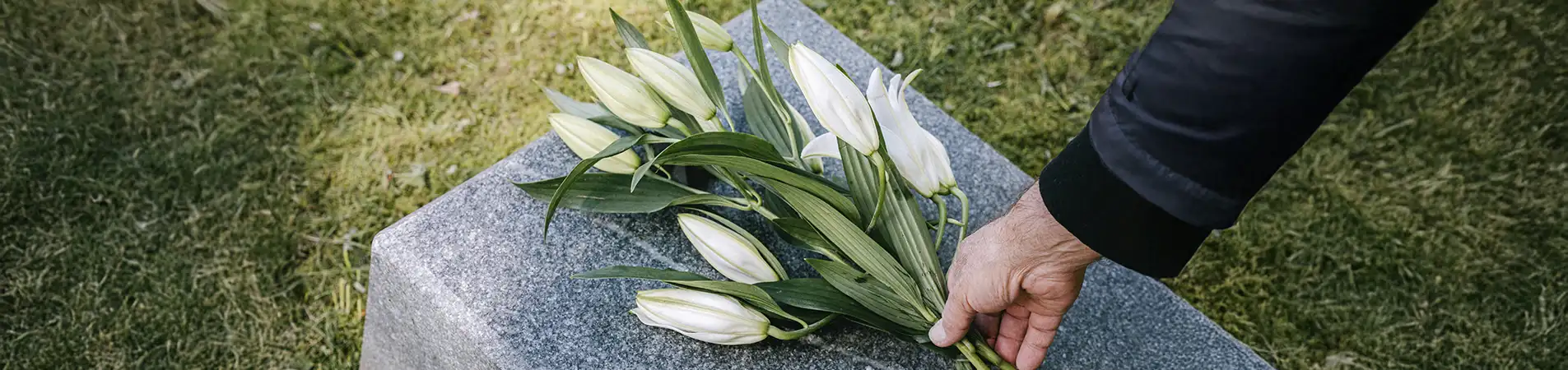 a person leaving flowers on a gravestone