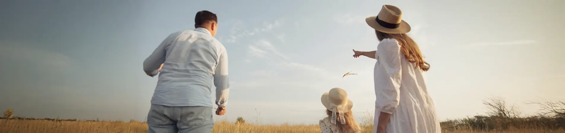 a family consisting of a father, a mother and their daughter playing in the field