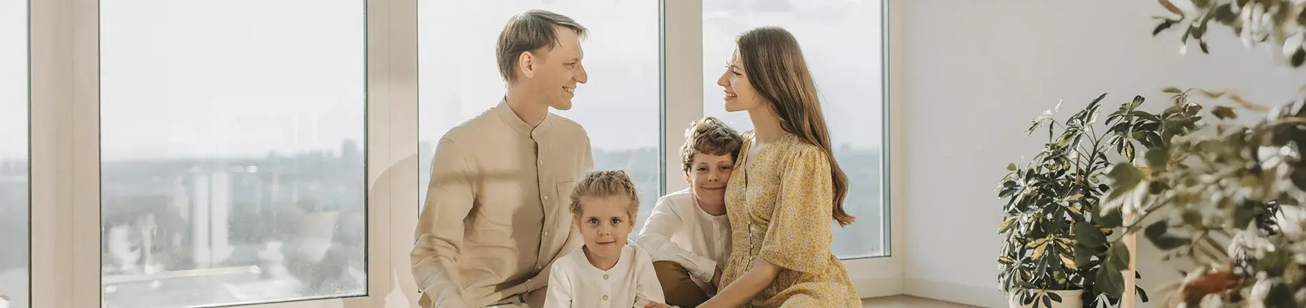 a family with two children posing for a photo in front of the window of their house