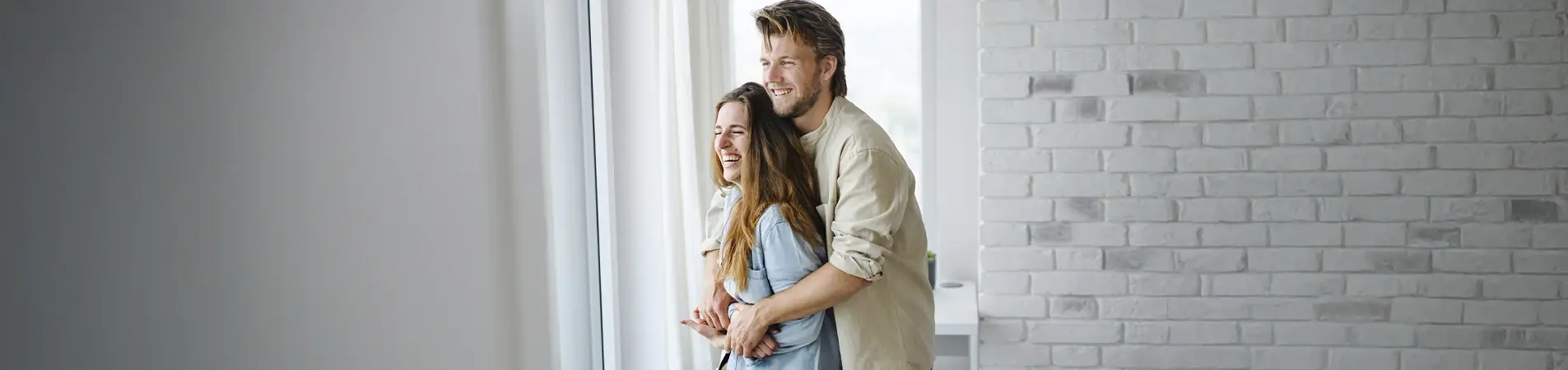 a couple looking out of the window of their new home