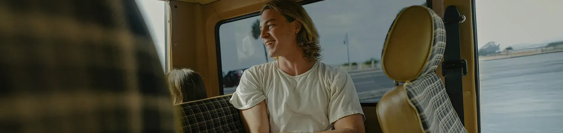 a boy in short sleeves laughing while travelling in a caravan