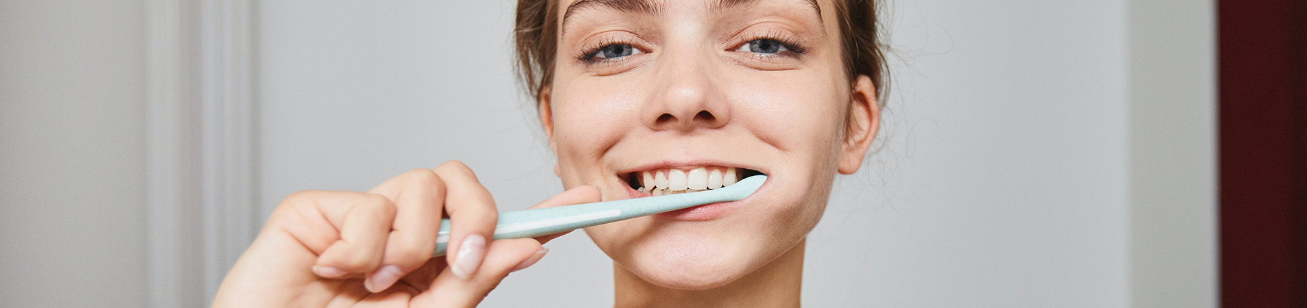 Girl brushing her teeth thinking of dental care insurance